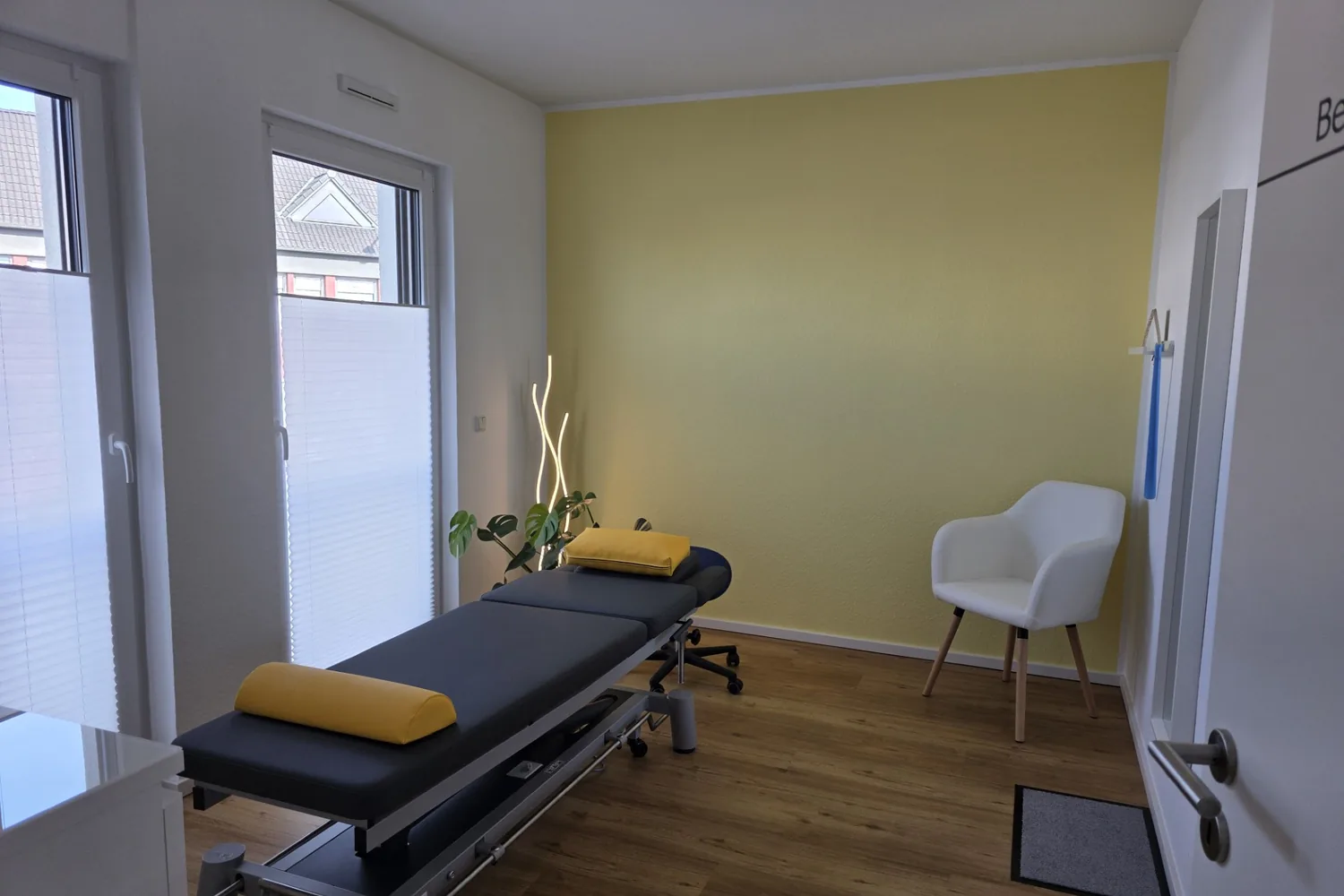 Behandlungsraum mit Therapieliege vor gelber Wand