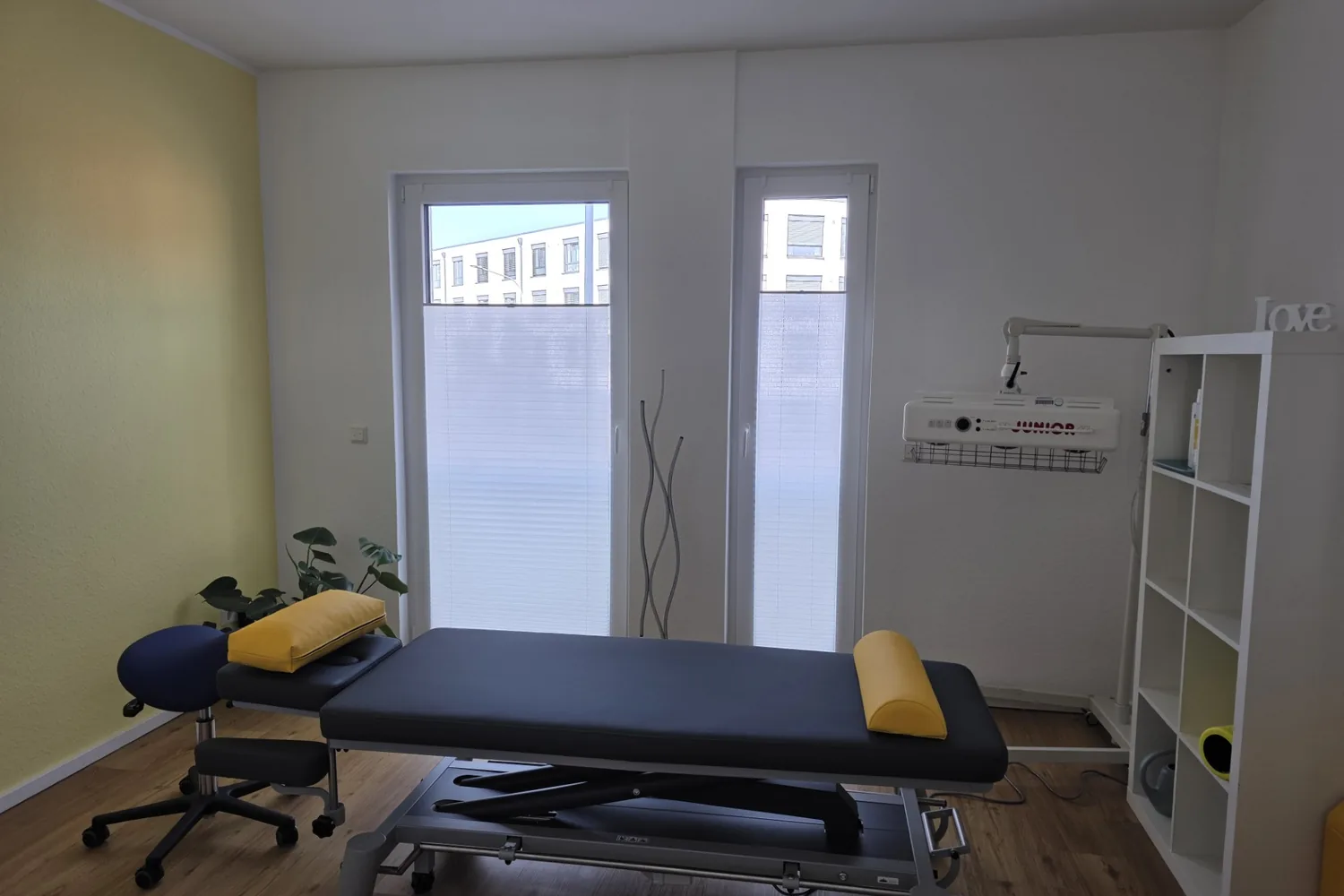 Heller Behandlungsraum mit Therapieliege und Wärmestrahler