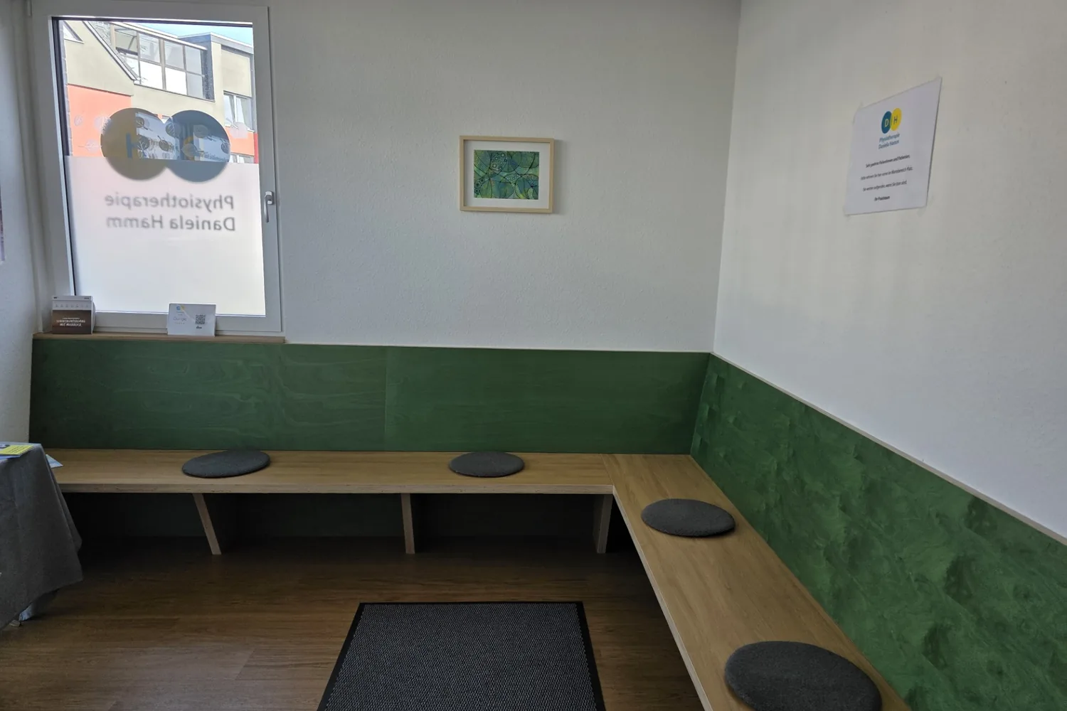Wartebereich mit Sitzbank aus Holz und grüner Rückwand