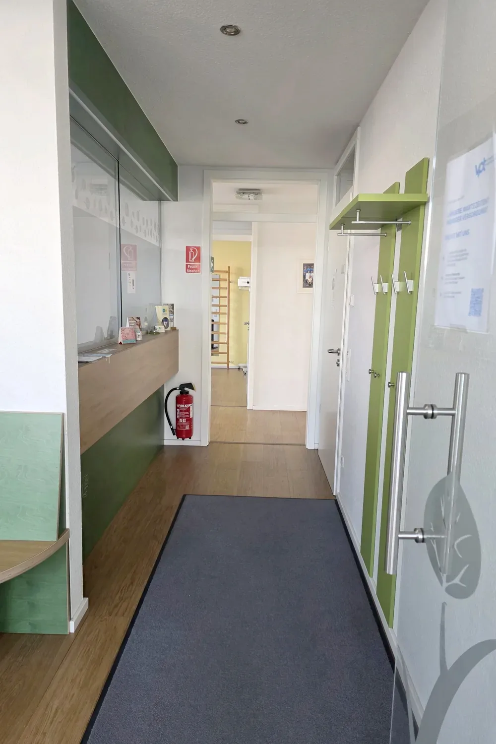 Empfang mit Garderobe und Blick in einen Behandlungsraum